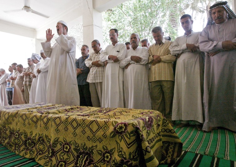 Men pray near the coffin of slain Iraqi interior ministry official Ibrahim Khamas during his funeral in Baghdad