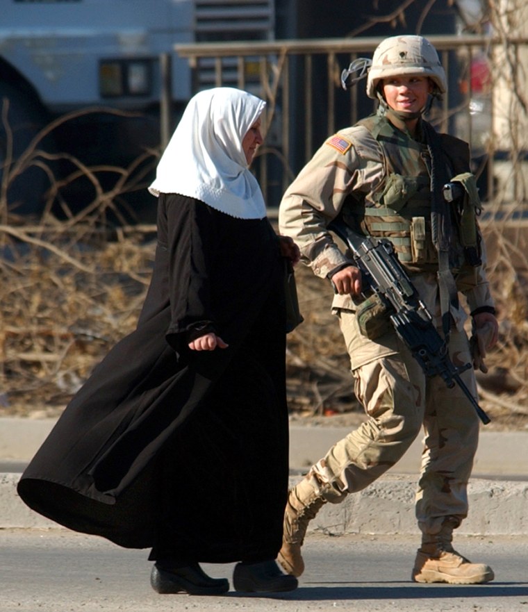 A female American soldier escorts an Iraqi woman away from the scene of a Baghdad suicide car bombing last November. Some 20 percent of U.S. combat support and service roles in Iraq are now filled by women.