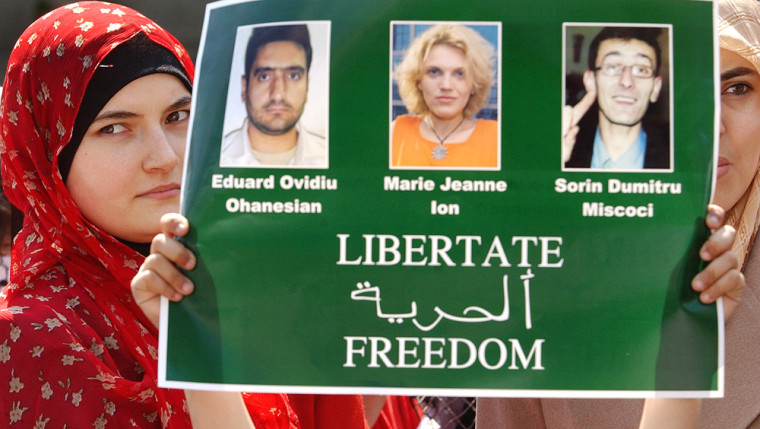 Women of the Romanian Arab community hold a poster showing the three Romanian journalists kidnapped in Iraq, during a protest held in Bucharest, Romania in April.