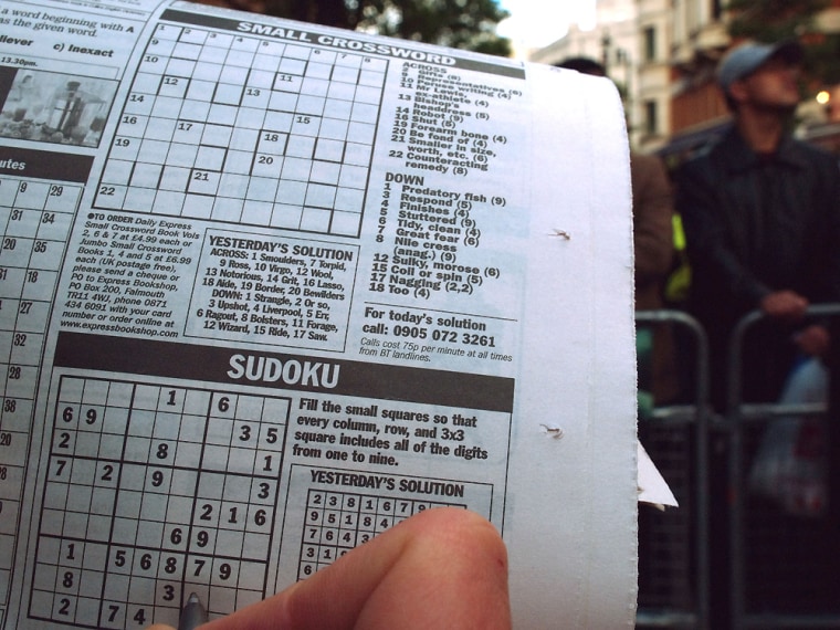 A fan attempts to complete a Sudoku puzzle in a newspaper in London's Leicester Square on Tuesday while in line for the premier of the film "House of Wax." 