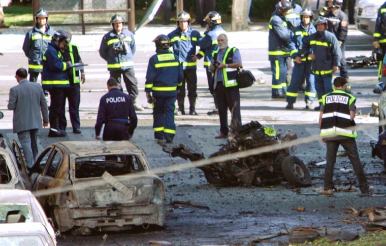 Spanish policemen and rescue workers inspect the scene after car bomb explosion in Madrid