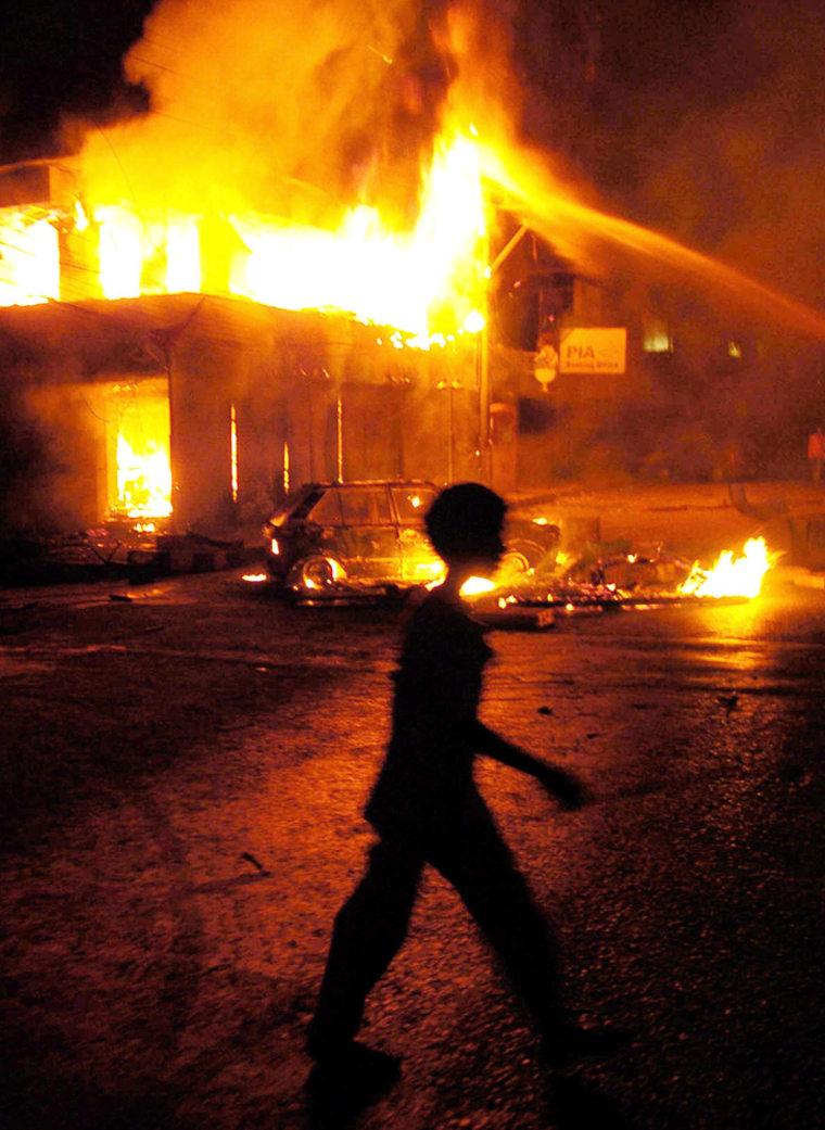 A Pakistani boy walks past a burning veh