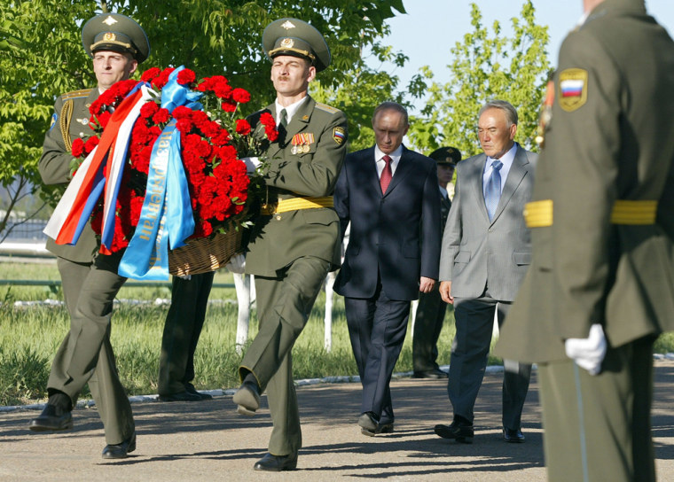 Russian President Vladimir Putin and Kazakh President Nursultan Nazarbayev walk behind two high-stepping members of an honor guard carrying a wreath during ceremonies to mark the 50th anniversary of the Baikonur Cosmodrome.