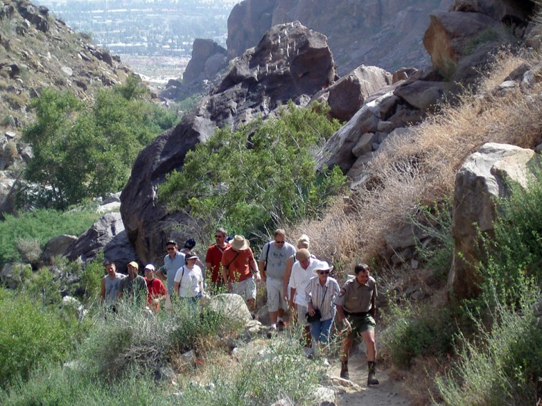 In this photo provided by the Agua Caliente Band of Cahuilla Indians, tribal ranger Robert Hepburn, right, leads a group of visitors through Tahquitz Canyon up to Tahquitz Falls near Palm Springs, Calif.