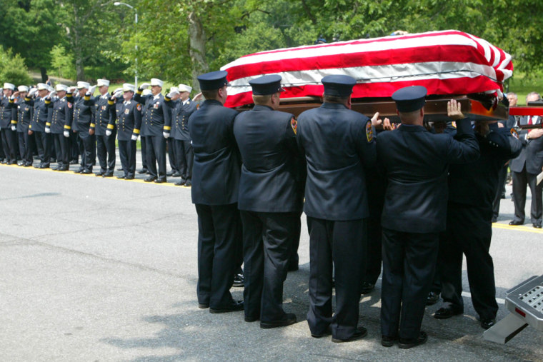 Firefighters unload a casket from a fire truck containing the remains of Kiethroy Maynard in New York City