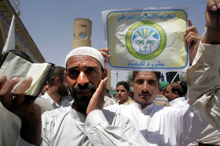 A demonstrator holds up a Quran while other holds poster of the Iraqi Islamic Party during a protest in front of Baghdad's Sunni Abu Hanifa Mosque Friday June 3.