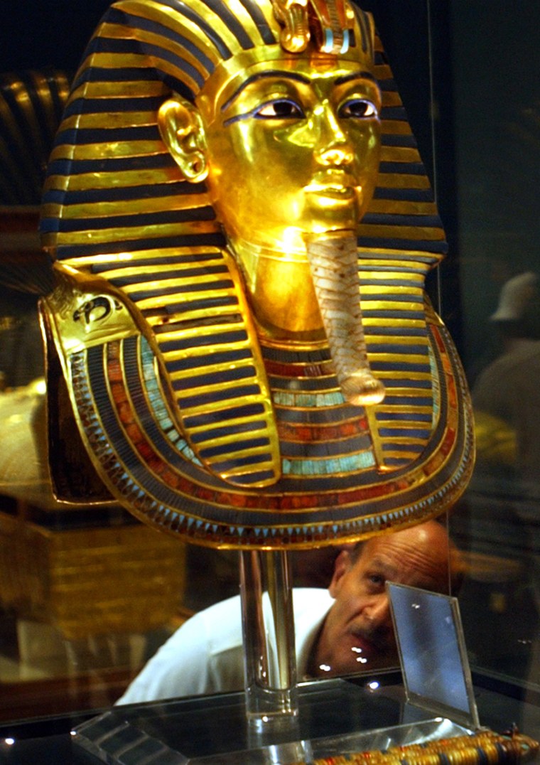 Tourists look to the gold mask of King Tutankhamun at the Egyptian museum in Cairo Wednesday, May 11, 2005. The first facial reconstructions of King Tutankhamun,who became pharaoh at the age of nine and the most famous Egyptian king in history, based on CT scans of his mummy have produced images strikingly similar to the boy pharaoh's ancient portraits, with one model showing a baby-faced young man with chubby cheeks and his family's characteristic overbite. (AP Photo/Amr Nabil)