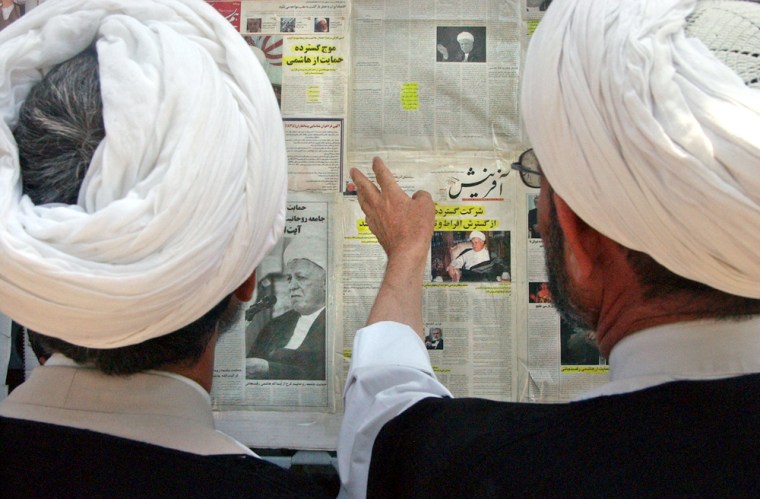 Two clergymen read newspapers Monday placed on the wall of a campaign center of former Iranian president Akbar Hashemi Rafsanjani, current presidential candidate, shown in the papers' pictures, who will face Tehran's hard-line mayor in Iran's first runoff presidential election in its history. 