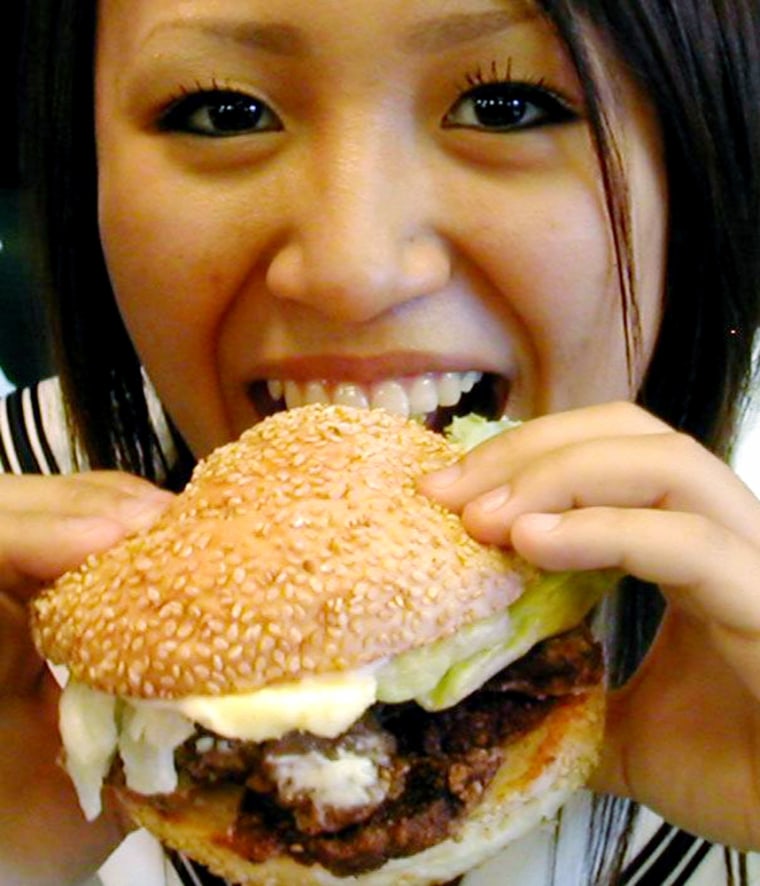 A young Japanese woman bites into a whale burger which went on sale at Lucky Pierrot in Hokkaido, Japan