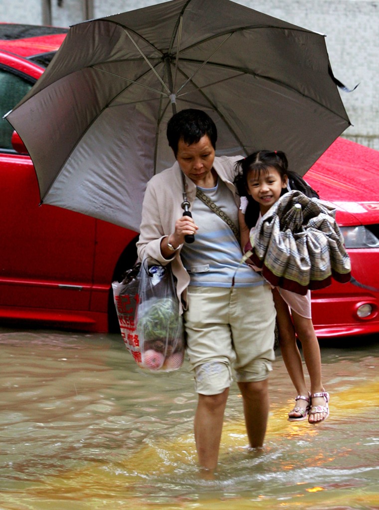 A woman carries a girl as she wades through flood waters, Hong Kong
