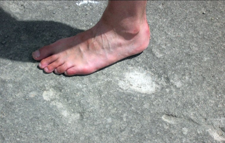 The apparent imprint of toes and a heel can be seen in hardened volcanic ash just below the bare foot in this image, taken at an abandoned Mexican quarry.