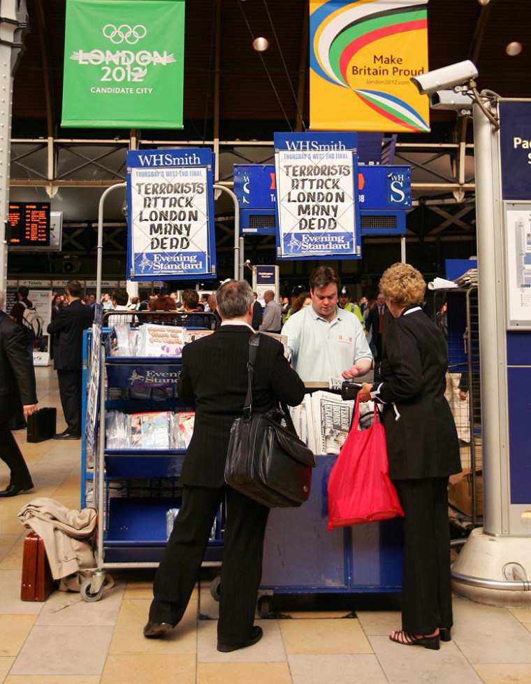 Commuters buy newspapers from at stand at Paddington Station in London