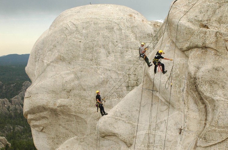 Knut Foppe, left; Darin Oestmann, center, with the National Park Service; and Thorsten Mowes, right, rappel down Thomas Jefferson's face Thursday to begin power washing Mount Rushmore National Monument.