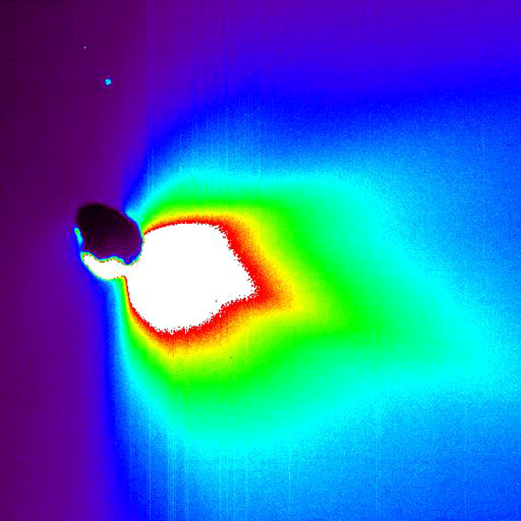 This false-color image shows Comet Tempel 1 about 50 minutes after Deep Impact's probe smashed into its surface. The comet itself is a backlit black blob. The colors represent brightness, with white indicating the brightest materials and black showing the faintest materials. This brightness is a measure of reflected sunlight. The sun is to the right, outside the image frame. The light spot above the comet is a star.