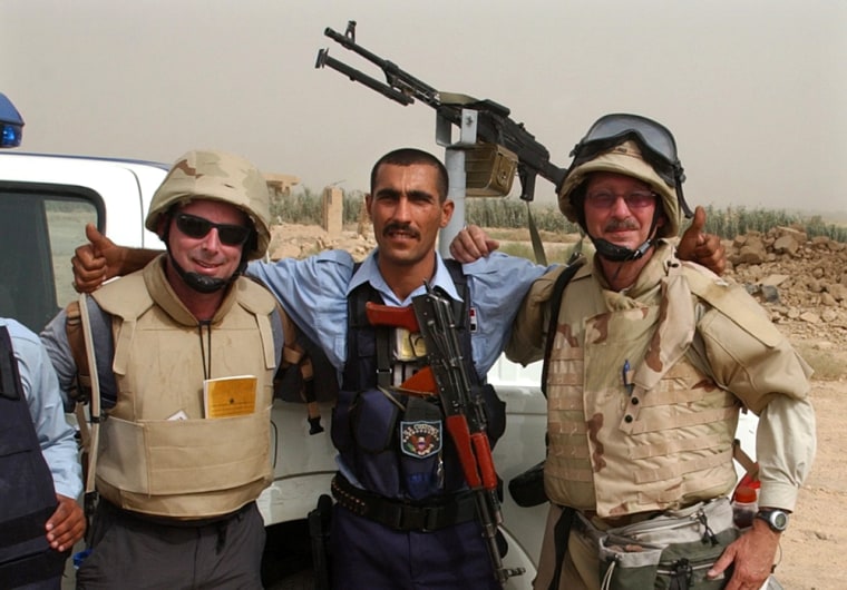 Atlanta Journal & Constitution reporter Dave Hirschman, left, and photographer Curtis Compton, right, meet Iraqi plice officers while riding in a Bradley mission with Alpha Company, 1st of the 121st, out of Lawrenceville, Ga., in June. Hirschman and Compton are embedded with the Georgia National Guard 48th Brigade.