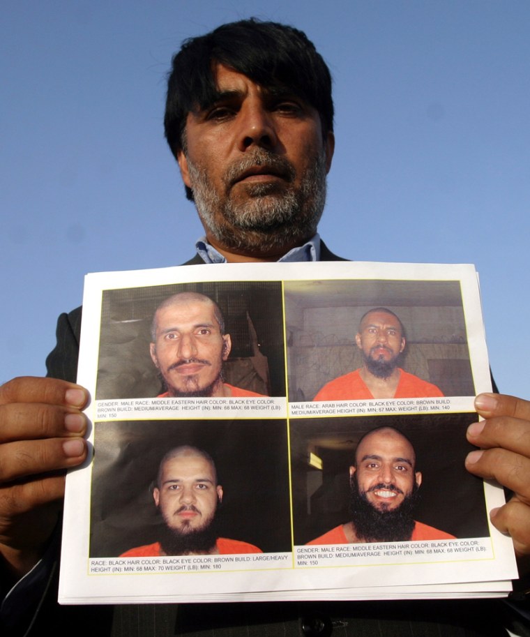 Chief of Bagram district holds leaflets with the photographs of four Arab al Qaeda militants who escaped from a detention centre in Afghanistan