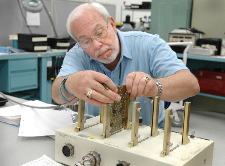NASA test engineer Lloyd Pierce checks electronic components related to the faulty readings from a low-level sensor in the shuttle Discovery's external fuel tank. 