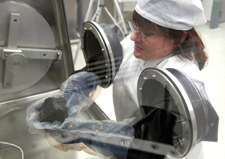 One of the Mars meteorites that provided data for the study, MIL 03346, is handled by a white-room worker in the meteorite processing laboratory at NASA's Johnson Space Center.