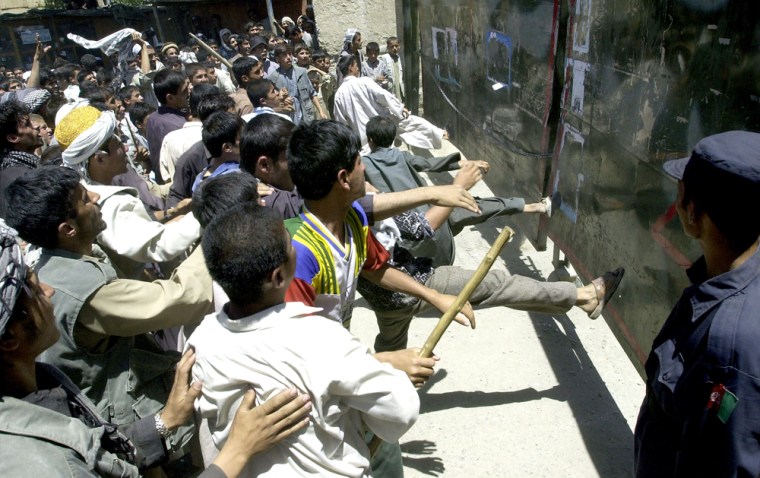 Afghan protesters kick towards a gate du