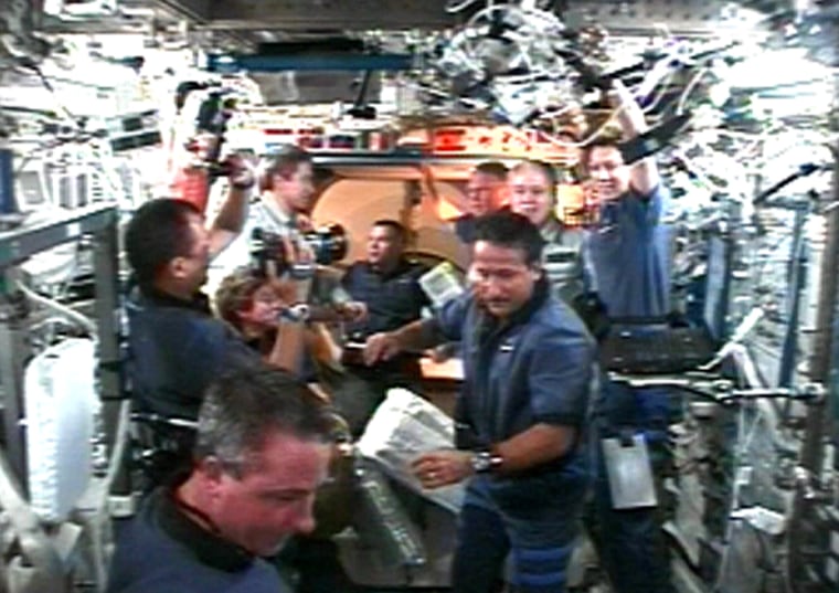 The shuttle Discovery's astronauts (in blue shirts) and the international space station's crew members (in gray shirts) greet each other in the station's Destiny laboratory after Thursday's docking.