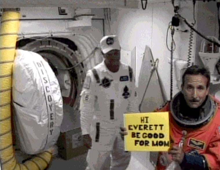 In this image from NASA Television, astronaut Charles Camarda holds a sign before entering the space shuttle Discovery for last Tuesday's launch. The sign tells his son Everett to "be good for Mom."