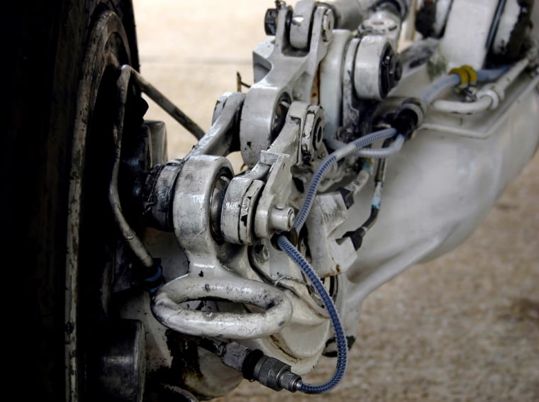 A detailed look at the left main landing gear of the F/A-18 Hornet at the Navy's test pilot school at Patuxent River Naval Air Station, Md., Wednesday, June 29, 2005, shows a tie-down ring, foreground, that is used to attach chains to secure the jet to the deck of an aircraft carrier. Chains can chafe against the antiskid braking system wiring shown to the ring's right. The wiring can then break, deactivating the system. At the Navy's direction, mechanics have begun wrapping the wires in clear, corrugated tubing to help prevent damage. (AP Photo/Ted Bridis)