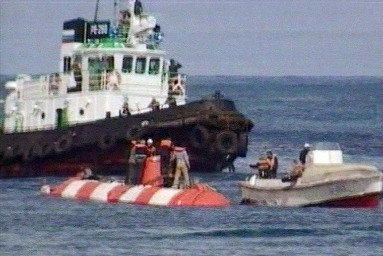 Crew members of the Russian mini-submarine and rescue team members stand on its hull (white and red streaks) shortly after the sub surfaced in the Beryozovaya Bay about 15 kilometers (10 miles) off the Kamchatka coast, Sunday, Aug. 7, 2005, in this image taken from television. A Russian mini-submarine that was trapped for nearly three days under the Pacific Ocean surfaced Sunday with all seven people aboard alive after a British remote-controlled vehicle cut away the undersea cables that had snarled it. (AP Photo/Russian Television Pool via APTN) ** TV OUT **