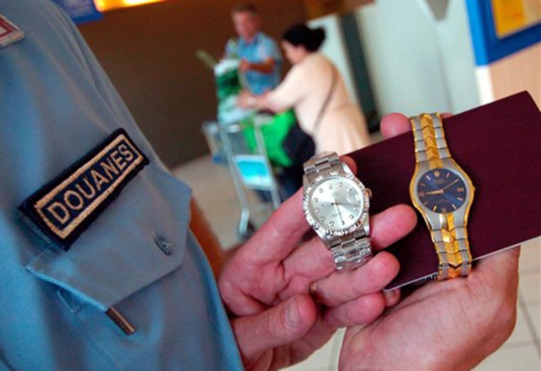 A French customs officer displays two fake Rolex watches discovered in the suitcase of a vacationer coming from Thailand.