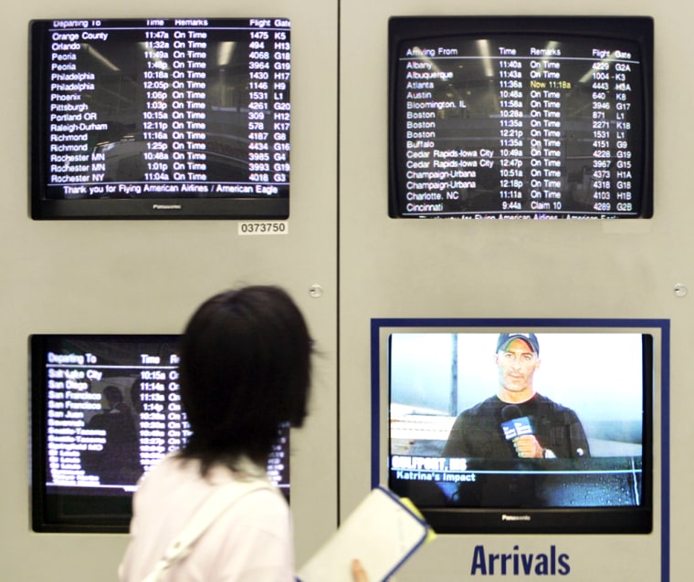 A traveler checks the departure monitors for any delays or cancellations at the American Airlines terminal at Chicago's O'Hare International Airport as another monitor airs a broadcast of the storm's impact to states along the Gulf Coast.