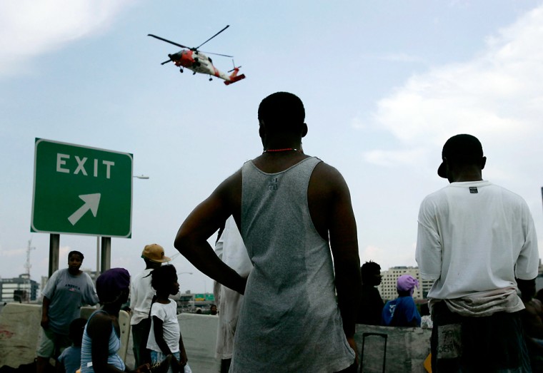 Stranded New Orleans residents watch as a helicopter evacuates others near the Superdome sports stadium