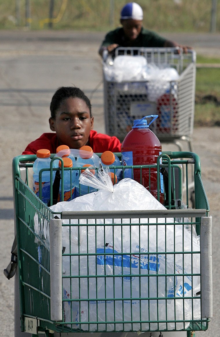 Ten-year-old Shirley Owen, front, and Tyronica Mabrey push shopping carts filled with drinks and ice down a street in Bay St. Louis, Miss., on Saturday, Sept. 3, 2005. Food, water and ice were being distributed throughout the town devastated by Hurricane Katrina. (AP Photo/Denis Paquin)