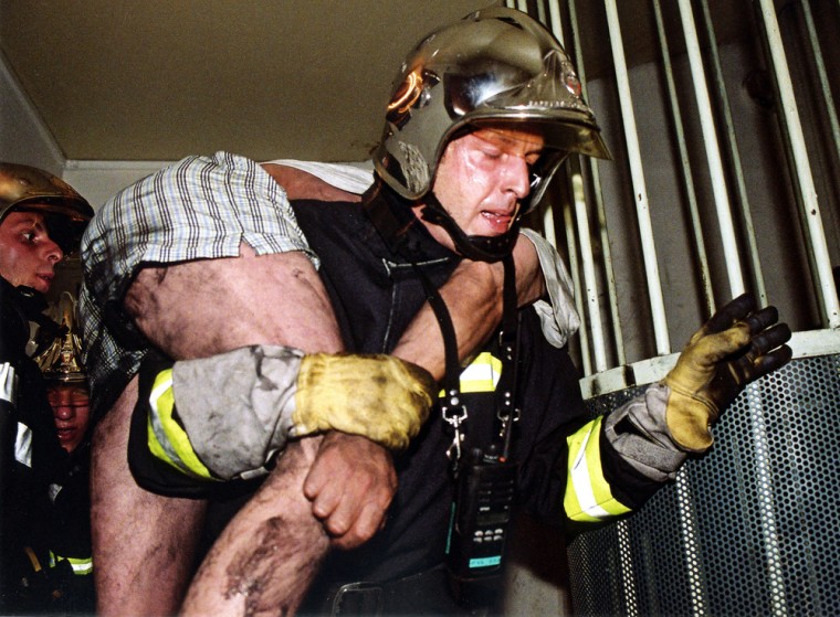 A firefighter evacuates a victim from a high-rise apartment building blaze in l'Hay-les-Roses, south of Paris, early Sunday.