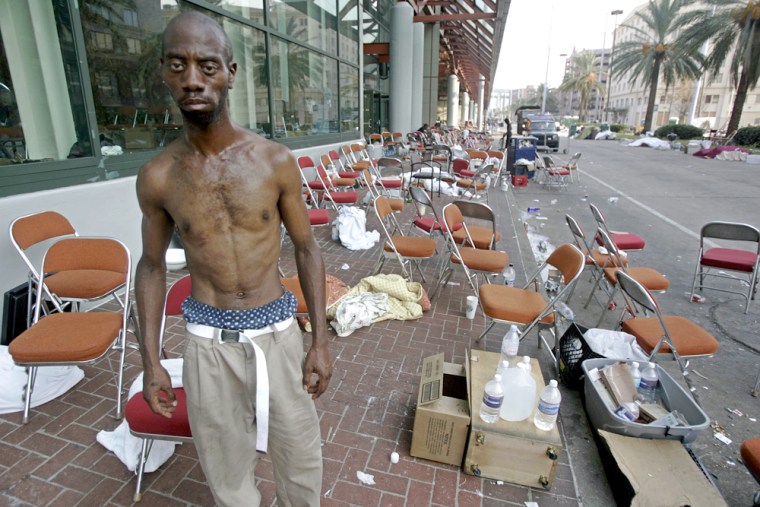 A homeless man stands near thousands of