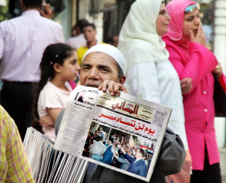 Egyptian street newspapers vender calls as he holds up a copy of Al-Ahram Al Massa'i newspaper with the headline, "A day that Egypt will never forget, Presidential election day," and a picture showing President Mubarak waving for supporters, in Cairo on Thursday.  
