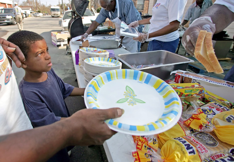 Dillon Nelly, left, waits for a meal with his father at a food distribution site organized by the Main Street Missionary Church in Biloxi, Miss., on Frday.