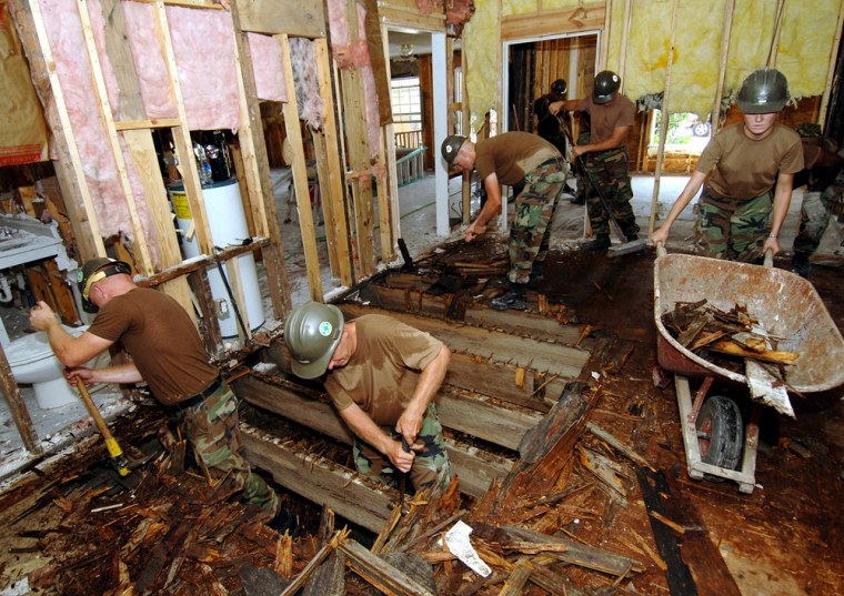 U.S. Navy Seabees tear through a plywood floor in support of Hurricane Katrina relief efforts in Waveland, Mississippi