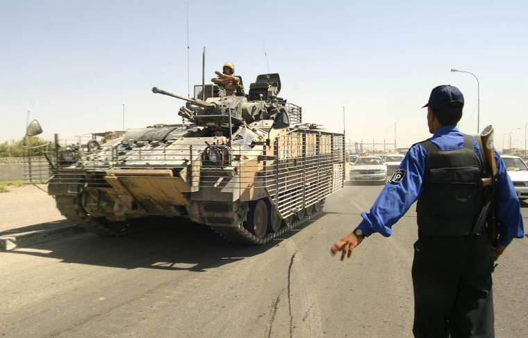 A British tank drives past an Iraqi poli