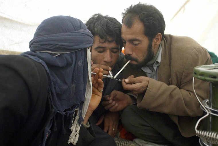 Iranian men smoke opium in a tent in the
