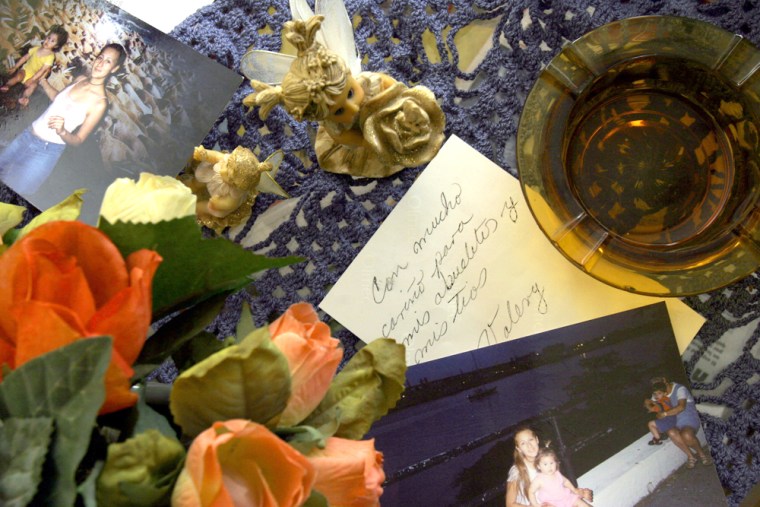 Pictures of Monica Lozada and her daughter Valery Belen Saavedra Lozada are seen over a table at  Lozada's family's house in the city of Cochabamba, Bolivia on Thursday, Oct. 6, 2005. The writing says \" To my grandparents and uncles, with love, Valery.\" Thousands of miles away from Queens, New York, in this colonial town in the heart of Bolivia, Monica Lozada's relatives are stunned by word of her killing, and are anxious to resolve a dispute over who should adopt Lozada's 4-year-old daughter who was found abandoned on the streets of Queens. (AP Photo/Dado Galdieri)