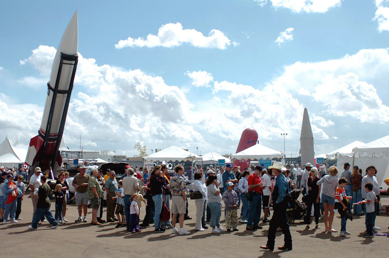 Visitors line up for food and souvenirs beneath and around looming private space vehicles during the final day of X-Prize Cup festivities at the Las Cruces International Airport, Sunday, Oct. 9, 2005, in Las Cruces, N.M. Visitors were able to meet and greet new space entrepreneurs on the cutting edge of the private space industry. (AP Photo/Alamogordo Daily News, Ellis Neel)