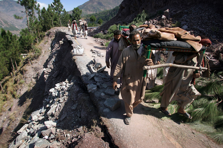 Pakistani men carry an injured man in a bed as they walk on an earthquake damaged mountain road near the village of Sanger, Pakistan, Wednesday Oct. 12, 2005.  Across the region of northwest Pakistan, destroyed by an earthquake, hundreds of villages remain cut off from help. (AP Photo/David Guttenfelder)