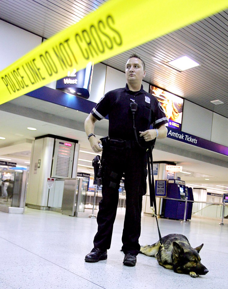 A police officer and a dog stand behind police lines in Penn Station in New York City