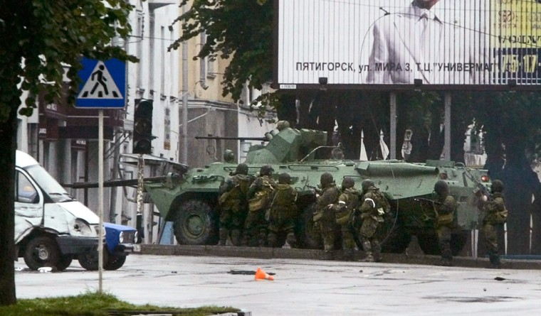 Russian special forces take cover behind an assault vehicle Friday as they approach a store in Nalchik where rebels had taken hostages.