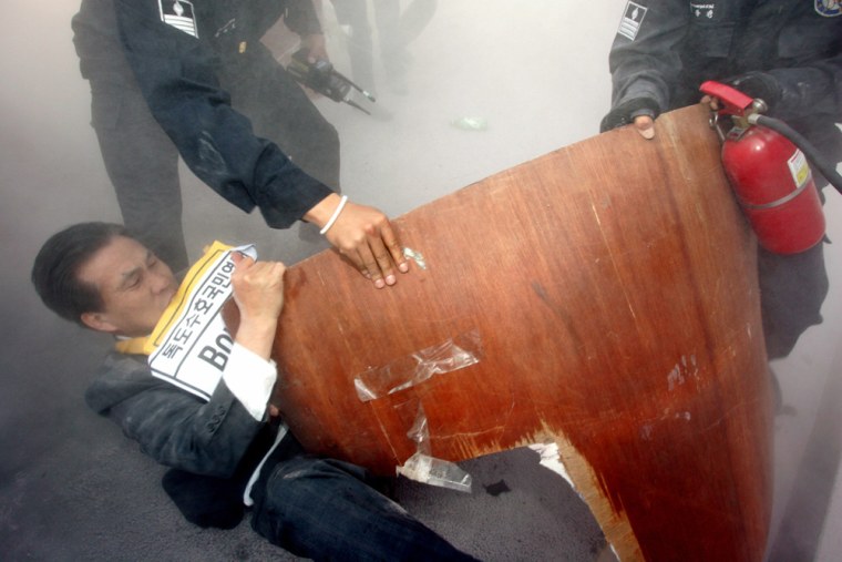 South Korean protester struggles as policemen try to snatch a sign during anti-Japan protest in Seoul