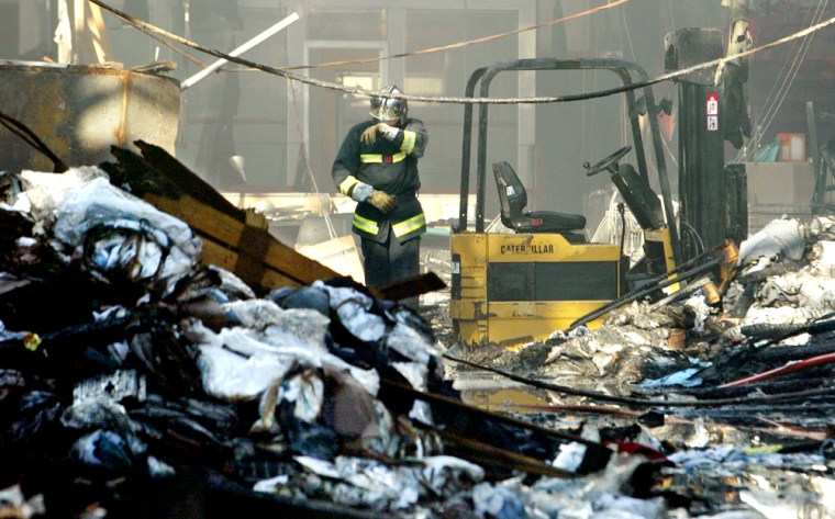 Fireman wipes his eyes as he walks through rubble of movie studio in Asnieres-sur-Seine, Paris