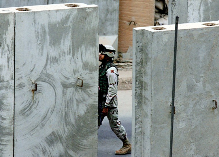 A U.S. soldier walks past concrete walls in Baghdad, Iraq, on Tuesday. The U.N. Security Council voted unanimously to extend by a year the mandate of the multinational force.