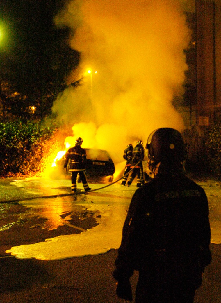 French firefighters try to extinguish a car set alight by rioters in Venissieux, a district of Les Minguettes,  near the central French city of Lyon, Sunday, Nov. 13, 2005. The nationwide storm of arson attacks, rioting and other violence has lost steam since Wednesday, when France declared a state of emergency. Youths set fire to 374 parked vehicles Saturday-Sunday, police said, compared to 502 the previous night.(AP Photo/Patrick Gardin)