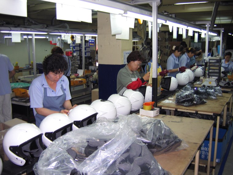 Workers on an assembly line make motorcycle helmets at HJC Helmets factory in Yongin, South Korea.