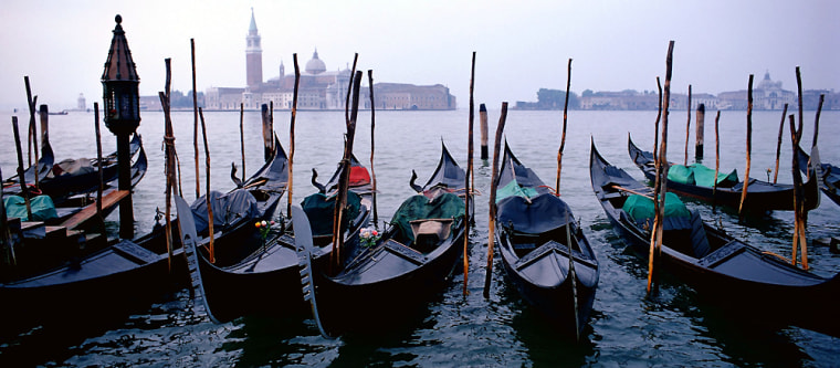 Gondolas line the bank near Venice's Grand Canal with the San Giorgio Maggiore church in the background.