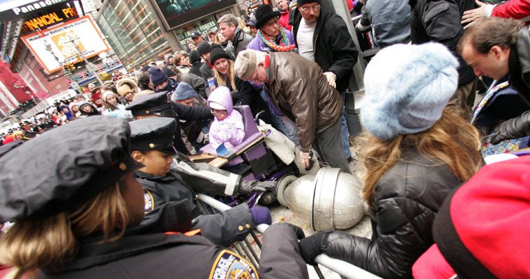 New York City police officers rush into the crowd after a street lamp head crashes to the ground during the Macy's Thanksgiving Day Parade, on Thursday, injuring two sisters.